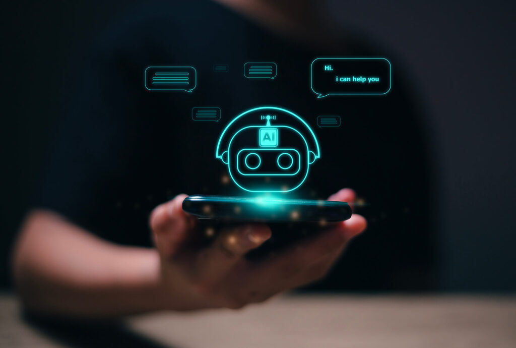 A hand holding a smartphone displaying a holographic AI chatbot with speech bubbles saying 'Hi. I can help you'.